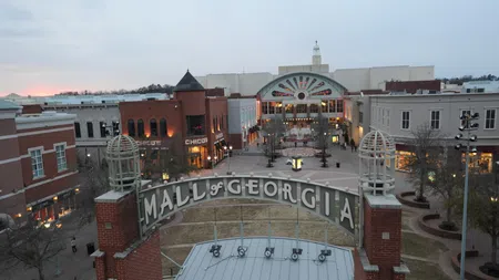 Evening view of the Mall of Georgia entrance with surrounding shops and buildings under a cloudy sky.