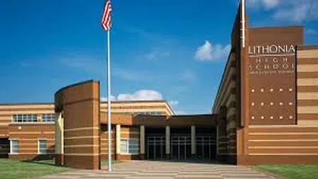 Exterior view of Lithonia High School building with American flag against a blue sky.