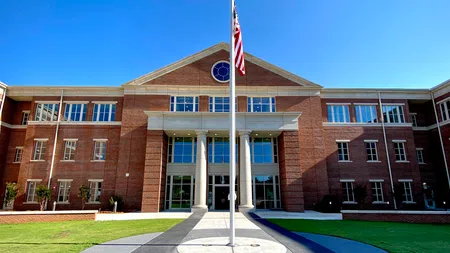Front view of a large red brick school building with white columns and an American flag in front.