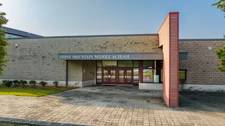 Front entrance of Stone Mountain Middle School with red doors and clear sky in the background.