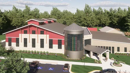 Modern community center with red and beige exterior, large windows, cylindrical glass entrance, and accessible parking.