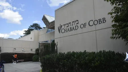 Exterior of the Chabad of Cobb building with signage, greenery, and a partly cloudy sky above.