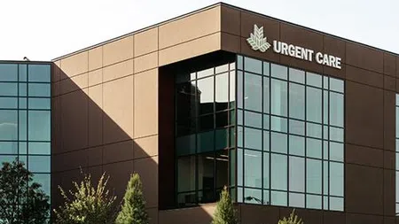 Modern urgent care building with large glass windows and workers landscaping the front lawn on a sunny day