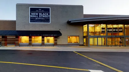 Exterior view of New Black Wall Street Market building with illuminated windows at dusk.