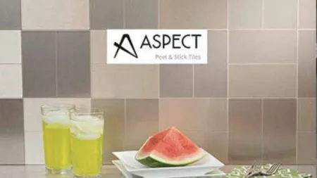 Watermelon slice on white plates with two glasses of yellow drink against beige tile backsplash