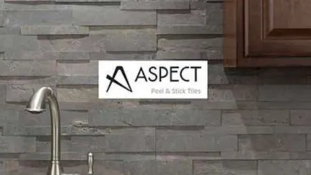 Modern kitchen backsplash with gray stacked stone peel and stick tiles behind stainless steel faucet.