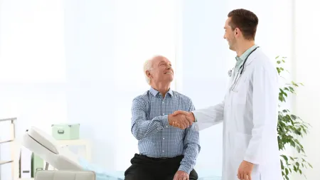 a person sitting on a chair talking to a person in a white coat