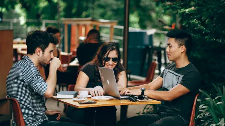 a group of people sitting around a table with a laptop