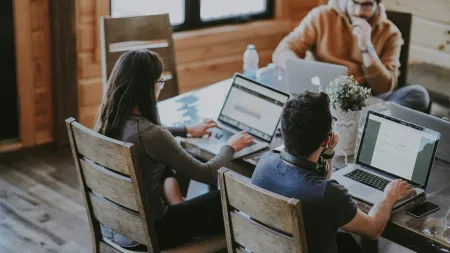 a group of people sitting at a table using laptops