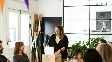 Group of coworkers enjoying snacks and drinks during a casual meeting with colorful bunting overhead