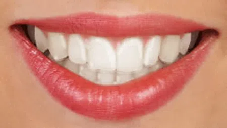 Close-up of a smiling mouth with red lipstick and clean white teeth showing.