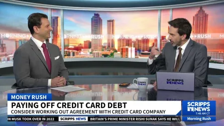Two news anchors discuss paying off credit card debt on Morning Rush with city skyline background and Scripps News branding.