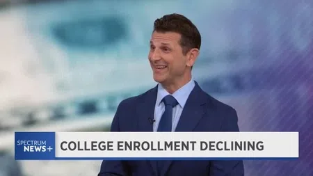 News anchor in blue suit reporting on college enrollment declining on Spectrum News Plus.