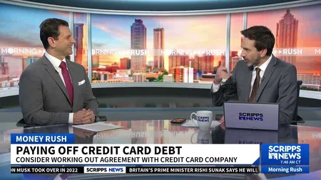 Two news anchors discuss paying off credit card debt on Morning Rush with city skyline background and Scripps News branding.