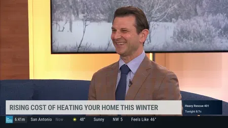 Smiling male news anchor discussing rising home heating costs on morning weather news show.