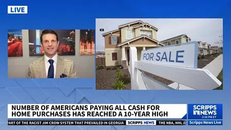 News segment showing a man reporting on rising cash home purchases with a for sale sign in front of a house.