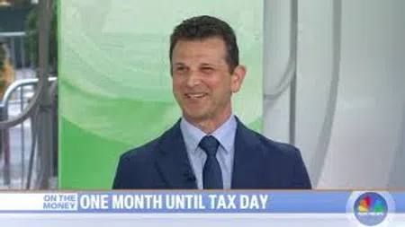 Man in blue suit and tie smiling during a TV segment with text about one month until tax day