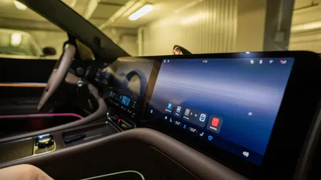 Close-up of a modern car interior featuring a wide touchscreen dashboard and steering wheel controls.