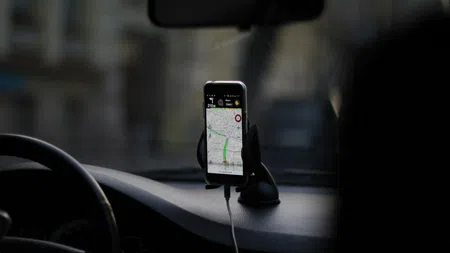 Smartphone mounted on car dashboard displaying GPS navigation with route guidance during a drive.