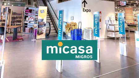 Entrance of Micasa Migros home goods store with escalator and product displays inside