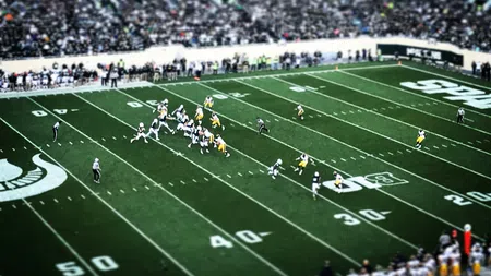Aerial view of a college football game with players on the field and a crowd in the stadium stands.