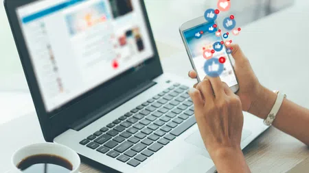a person holding a remote control in front of a laptop