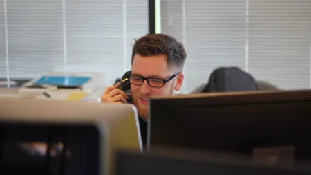 a person sitting at a desk with a phone