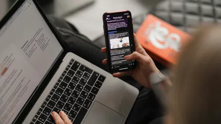 a person holding a phone and a laptop