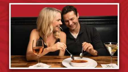 a man and woman sitting at a table with food and drinks