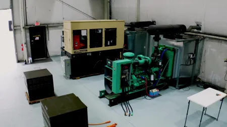 Industrial generator and machinery setup in a clean factory room with equipment and cables on the floor.