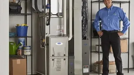 Technician standing next to a modern furnace and organized shelving in a clean utility room.