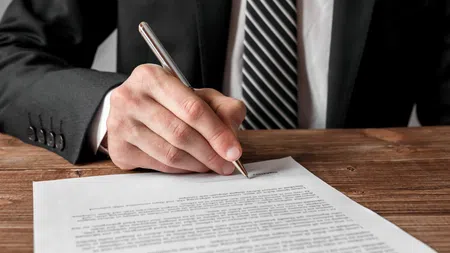 a man in a business suit signing a document