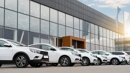 several white cars lined up in front of a car dealership