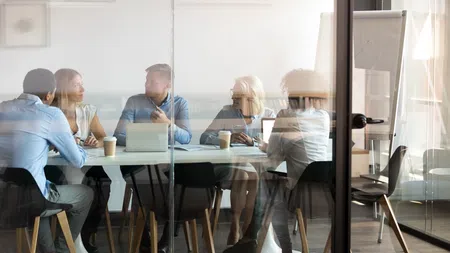 Diverse business team discussing ideas around a conference table in a modern glass office during a meeting
