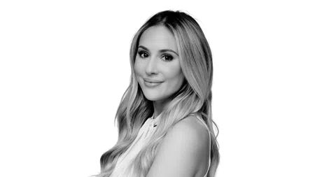 Black and white portrait of a smiling young woman with long wavy hair in a sleeveless top.