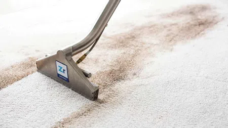 Professional carpet cleaning tool removing dirt from white carpet, showing clean and dirty contrast.