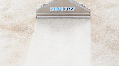 Carpet cleaning tool with Zerorez logo removing dirt and stains from beige carpet, revealing clean white fiber.