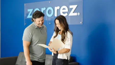 Man and woman reviewing documents together in front of a blue wall with Zerorez logo in the background.