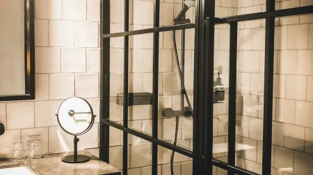 Modern bathroom with black framed glass shower enclosure, white subway tiles, and vanity with mirror and towel.