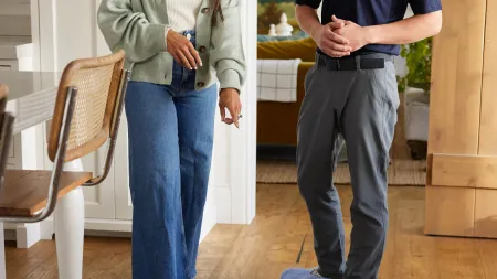 a man and a woman standing in a room looking at wood floors