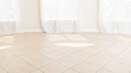 a tan tiled room with white thin curtains hanging in winter