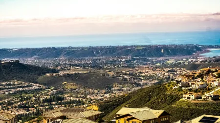 Scenic view of southern California with hills, houses, ocean in the distance, and clear sky at sunset.