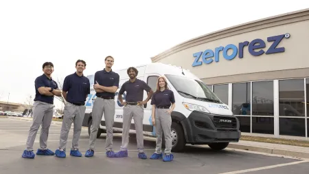 Five Zerorez employees in uniform standing in front of a branded van and company building with logo.