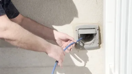 Person cleaning a dryer vent with a blue brush, ensuring optimal airflow and safety.