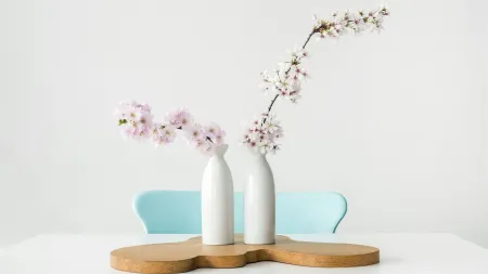 a couple of white vases with flowers in them