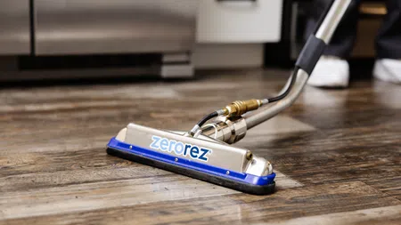 Zerorez cleaning equipment cleaning a wooden floor showing the contrast between cleaned and uncleaned areas.