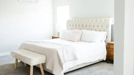 replace carpet in home before selling to increase curb appeal and get top dollar - bed with a white leather tufted headboard in a carpeted bedroom