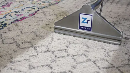 Carpet cleaning machine cleaning a patterned rug, showing a clear clean strip on the carpet.