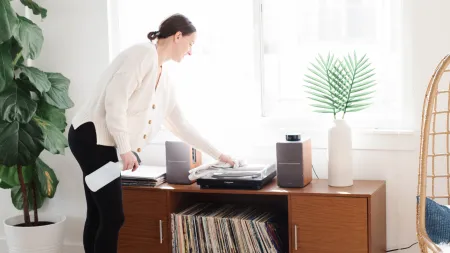 woman dusting off a vinyl record player on a decorated music side table