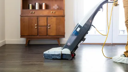 a person holding a vacuum cleaner on a hardwood floor